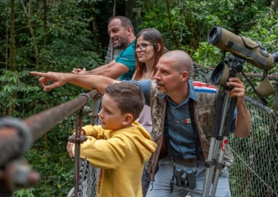 Family with a guide observing wildlife from a hanging bridge in Costa Rica.