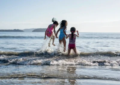 Three kids playing and jumping in the shallow waves at Las Catalinas beach in Costa Rica.