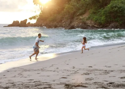 Family with kids running on a quiet beach in Costa Rica at sunset