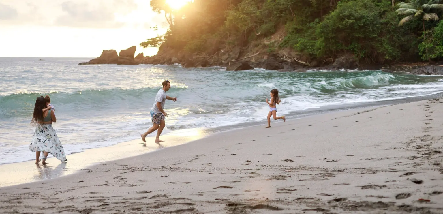 Family with kids running on a quiet beach in Costa Rica at sunset