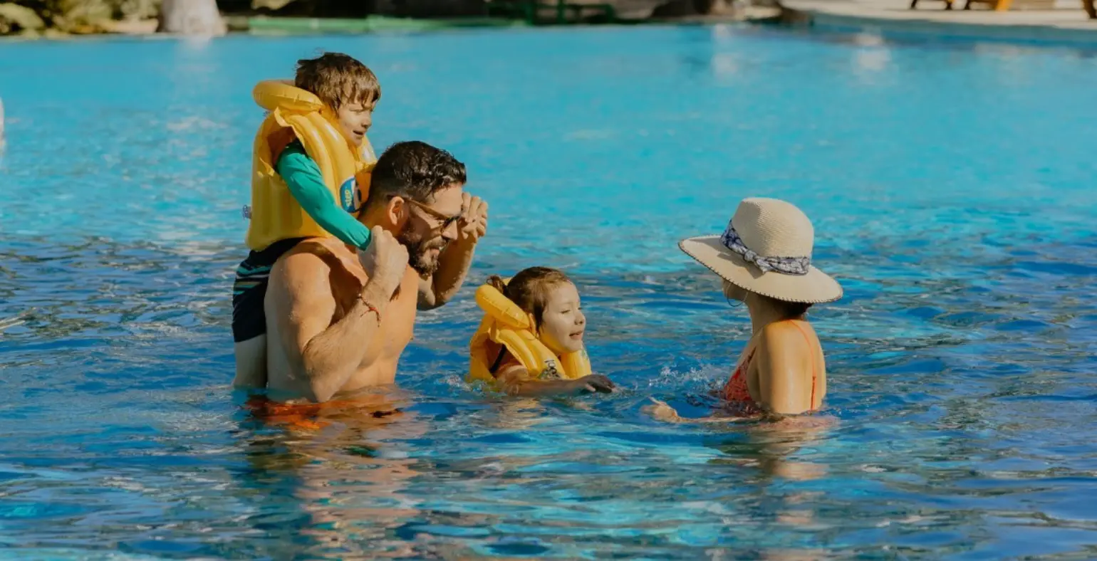 Family with kids playing together in a sunny pool in Costa Rica