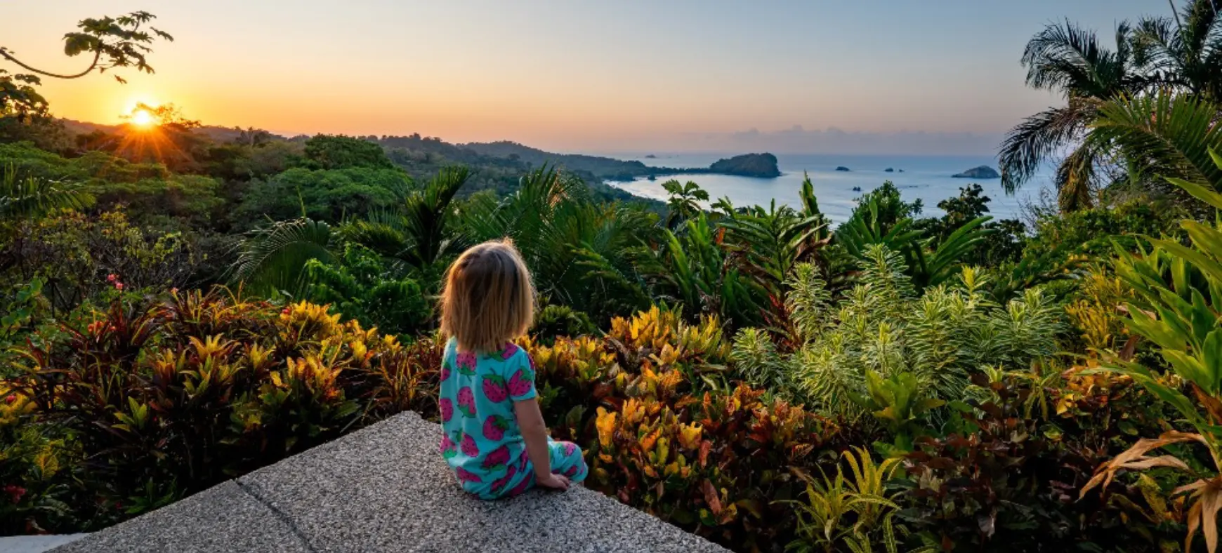 Young girl watching a colorful sunset over the Costa Rican coast