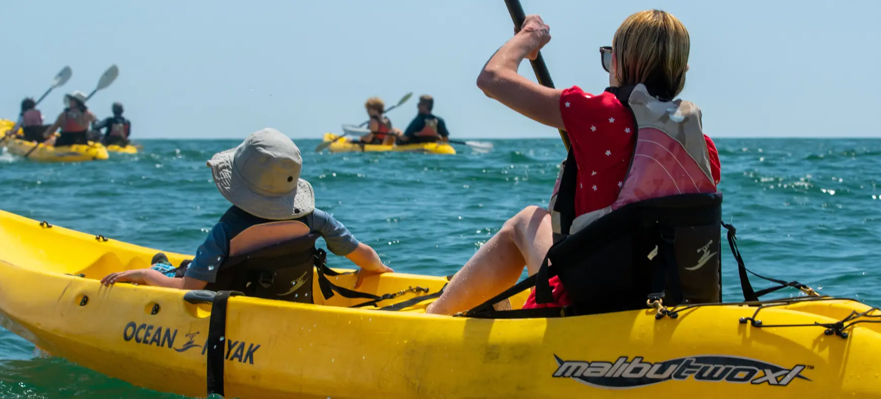 Mom and her kid paddling a yellow kayak on calm ocean waters in Costa Rica